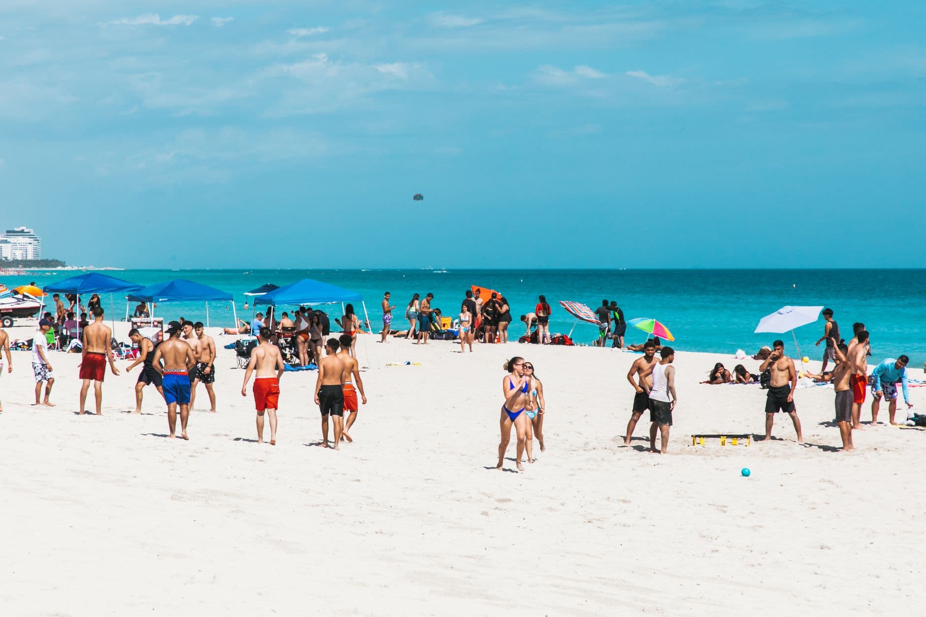 Groups enjoying volleyball and relaxation on sunlit Miami Beach.